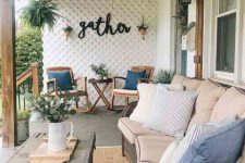 a rustic porch with wooden rockers, a coffee table, potted greenery, a wicker sofa with printed pillows and a chest coffee table
