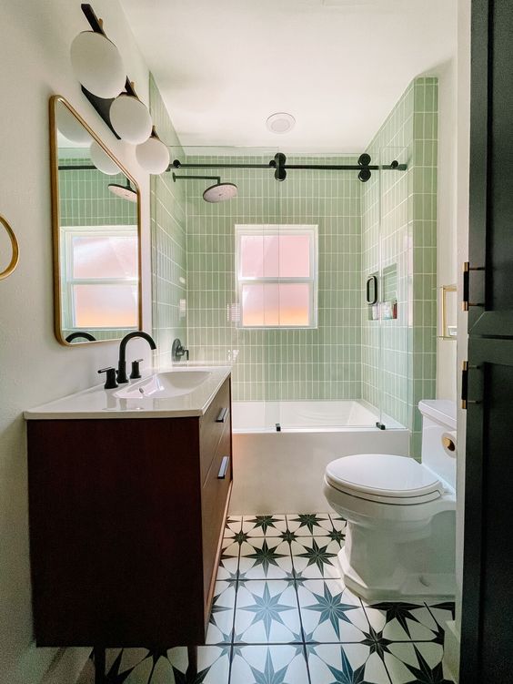 A small and cool mid century modern bathroom with skinny green tiles, a printed tile floor, a stained vanity, white appliances