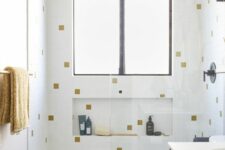 a small modern bathroom with catchy tiles with gold touches, a tub, a stained vanities, white appliances and black fixtures