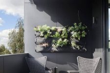 a stylish balcony with grey walls, woven chairs, a cool round table and potted greenery is a laconic and bold space to enjoy