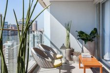 a stylish modern balcony with a brigth stained table, a couple of curved chairs, statement potted plants and a candle lantern