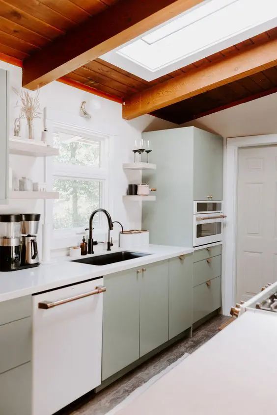 a welcoming mid century modern kitchen in light green, a skylight, a stained wood ceiling, white stone countertops