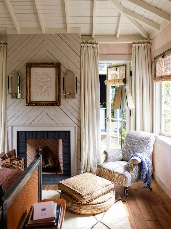 an eclectic vintage bdroom with pink walls, a planked chevron accent and a fireplace, neutral and pastel textiles, a black vintage bed