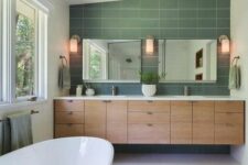 an elegant mid-century modern bathroom with green and white tiles, a large double vanity built-in, two mirrors and a large tub