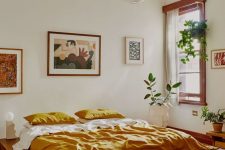 an elegant mid-century modern bedroom with a stained bed with no nightstands, a mini gallery wall, potted plants and bold bedding and a rug