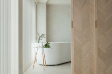 beautiful chevron pattern wooden sliding doors delicately separate the bathroom from the rest of the space and add interest