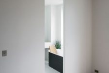 sleek and minimalist white sliding doors that look like a wall and separate the bathroom from the bedroom