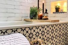 02 a beautiful bathroom with white tiles and bold navy Moroccan tiles covering the floor and the bathtub, a niche with lights and potted greenery