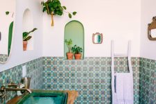 08 a bright bathroom with colorful Moroccan tiles and blue chevron tiles on the floor, a turquoise glass sink and potted plants