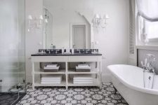 24 a vintage black and white bathroom with a neutral vanity, black countertops, a shower space, a vintage tub, vintage sconces and shutters on the wall