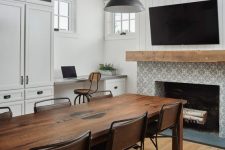 27 a black and white dining room with white walls, a built-in desk and a storage unit, a fireplace clad with Moroccan tiles, a rich-stained dining table and leather chairs