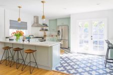 30 a pretty mint green kitchen with a Moroccan tile floor, brass pendant lamps, woodne stools and black fixtures is a beautiful space