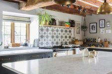 a beautiful farmhouse kitchen with graphite grey cabinets and white stone coutnertops, wooden beams on the ceiling and a star print tile backsplash