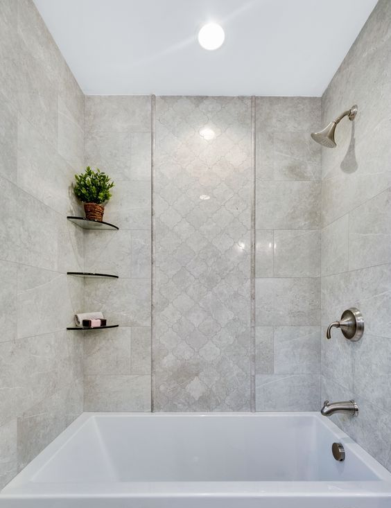 a beautiful neutral bathroom clad with white stone and arabesque tiles, a square bathtub, glass shelves and brushed fixtures is amazing