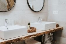 a beautiful organic bathroom covered with wood-looking tiles, a living edge vanity, two square vessel sinks and round mirrors in frames