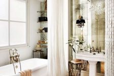 a beautiful vintage bathroom with a pedestal sink, a mirror wall, a crystal chandelier, open shelves and a tub plus a gorgeous curtain is pure chic