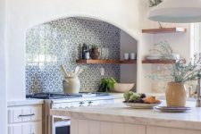 a beautiful white kitchen with planked cabinets, a blue Moroccan tile backsplash, stained stools and pendant lamps is cool