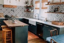 a black farmhouse kitchen with a kitchen island, stained wooden shelves, a bold black and white Moroccan tile backsplash