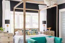 a bright glam bedroom with black walls, a wooden canopy bed, a turquoise loveseat, a beaded chandelier and wooden nightstand