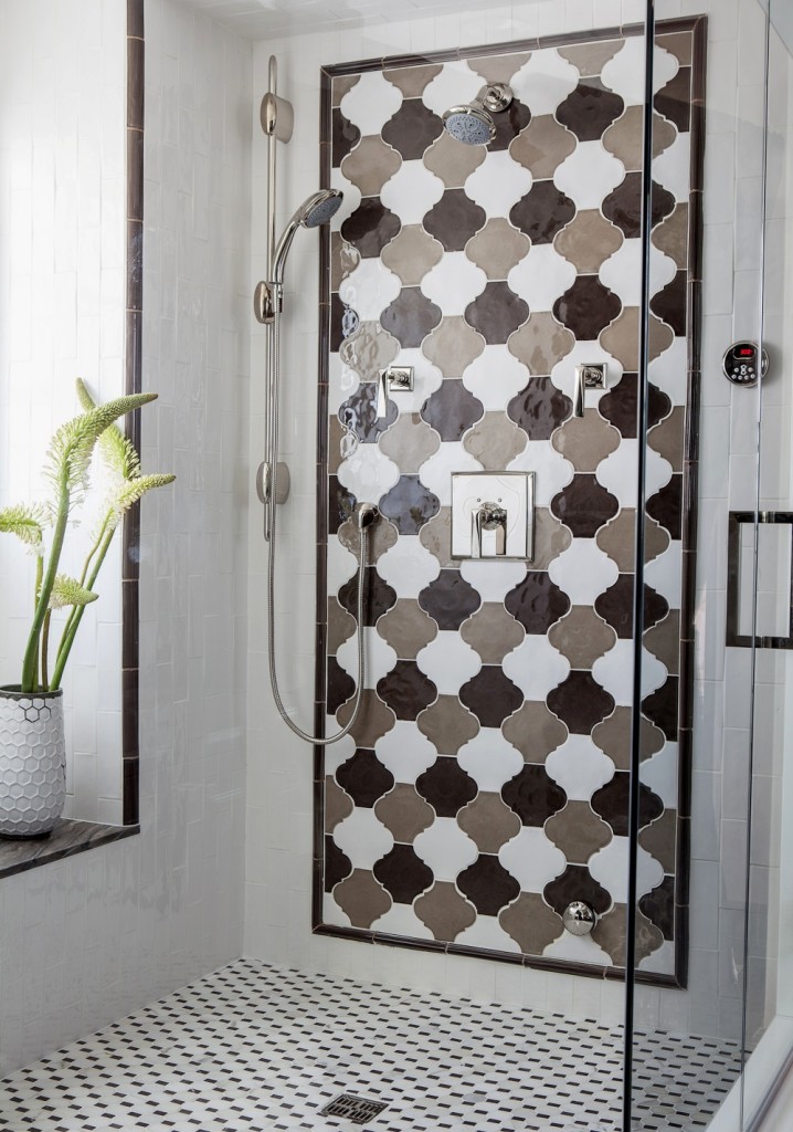 a bright shower space clad with geometric tiles and a bold monochromatic arabesque tile accent is super cool