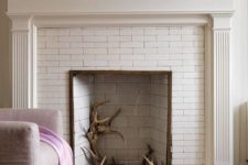 a built-in fireplace clad with white bricks is used to display antlers to give a slight woodland feel to the room