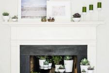 a built-in fireplace with a white mantel, a whole arrangement of potted succulents on display and some candles and artworks for a breezy look