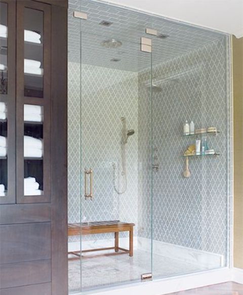 a chic bathroom with blue arabesque tiles in the shower, a stained bench and a dark stained storage unit is a very elegant and cool space