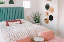 a colorful boho bedroom with a green upholstered bed, a gallery wall, pink chairs, hats on the wall as decor