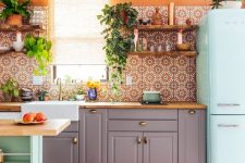 a colorful kitchen with grey cabinets, a mint green fridge and kitchen island, butcherblock countertops, orange walls and bright Moroccan tiles