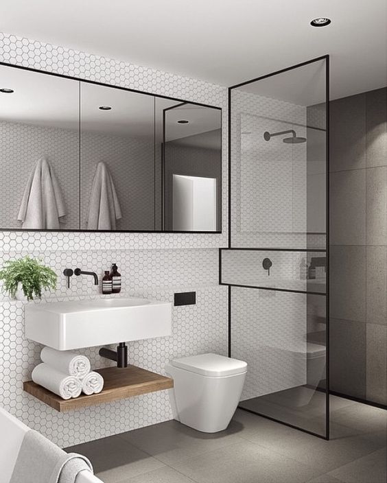 a contemporary bathroom clad with hex tiles, grey large scale ones, a shower space, a large mirror and a floating sink and shelf