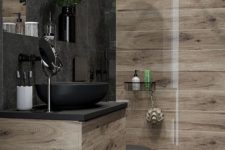 a contemporary bathroom clad with wood look and stone tiles, with a wooden and metal vanity, black appliances and black fixtures is stylish