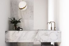 a contemporary bathroom in grey and white, with a grey floor, grey stone tiles, a floating stone sink and an open shelf, a cool pendant lamp is amazing