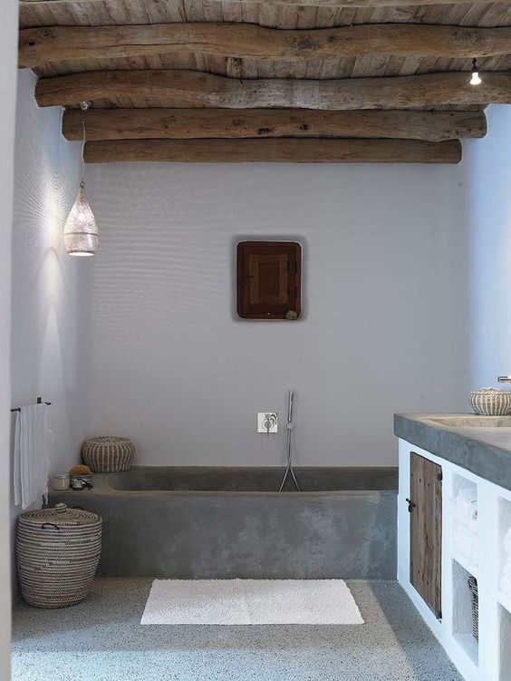 a contemporary bathroom with a tub of concrete and a terrazzo floor, a wooden ceiling with beams, a floating vanity with a concrete countertop