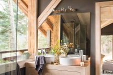 a contemporary bathroom with concrete walls and a floor, wooden beams and pillars, a matching vanity with two sinks and a shower space plus a view