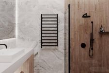 a contemporary bathroom with stone and wood look tiles, a wooden vanity, a white sink, black fixtures and built-in lights