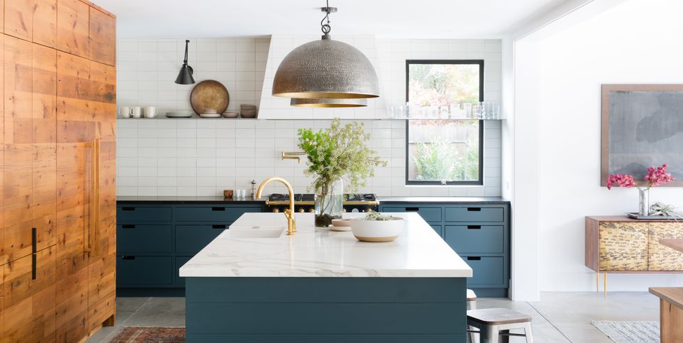 a contemporary blue kitchen with a white tile backsplash, a white hood and a skinny floating shelf for storage