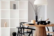 a cool Japandi dining room with a large white storage unit, a round table, black and neutral chairs, a pendant lamp and black tableware