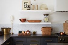 a cool eclectic kitchen with navy lower cabinets and a kitchen island plus white floating shelves instead of upper cabinets