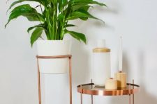 a copper round table with candles and a copper plant stand with a statement plant are great for styling a modern space