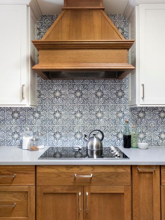 a cozy kitchen with stained and white cabinets, blue Moroccan tiles on the backsplash, white countertops is a chic idea