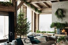 a cozy modern rustic living room with a fireplace, a grey sectional, a wooden coffee table and lots of evergreens for Christmas