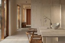 a dreamy Japandi kitchen with sleek cabinets, a large kitchen island, woven chairs and large floor to ceiling windows