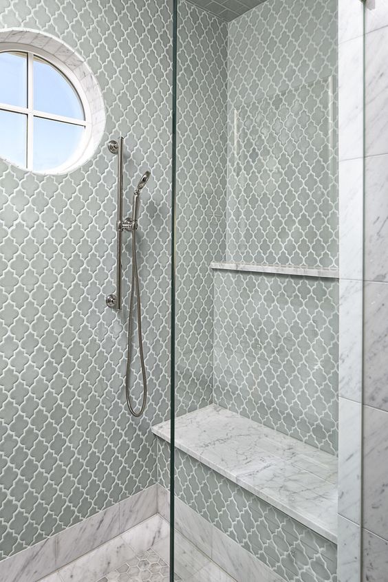 a fab shower space clad with slate grey arabesque tiles, with white stone ones and with a round mirror for natural light