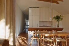 a gorgeous Japandi space with light-stained wooden floors, a dining set, wooden beams on the ceiling with a skylight is very airy