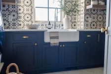 a gorgeous bold blue farmhouse kitchen with pretty Moroccan tiles on the walls and a backsplash, with open shelves and marble hex tiles on the floor