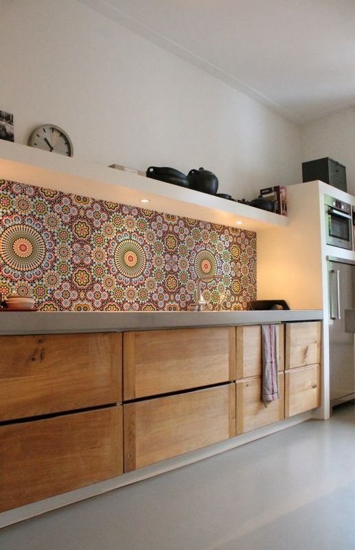 a gorgeous contemporary kitchen with light stained cabinets, an open storage shelf, built in lights, a bright Moroccan tile backsplash