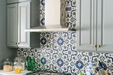 a gorgeous grey farmhouse kitchen with white stone countertops, a bright Moroccan tile backsplash and metallic touches is very elegant