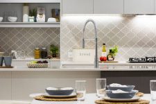 a grey and white contemporary kitchen with a grey arabesque tile backsplash, built-in lights and open storage shelves