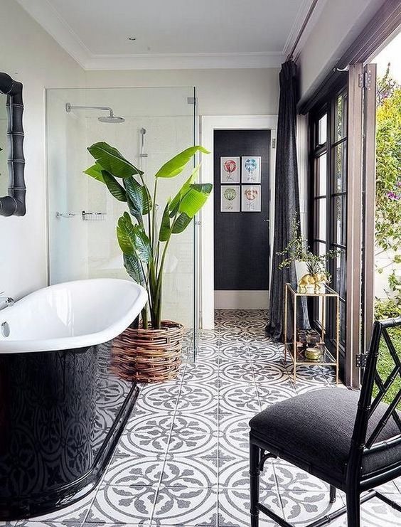 a lovely modern bathroom with a door to the garden, a shower, a black sleek bathtub, a black chair and cool tiles on the floor