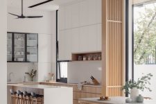 a lovely neutral Japandi interior with sleek white and light-stained cabinets, with a white kitchen island, a wooden slab divider, a laconic dining set